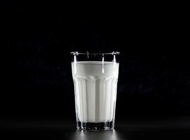 Glas mit Milch auf schwarzem Hintergrund
