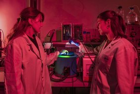 Um die Zapfenopsine nicht versehentlich zu aktivieren, führen die PSI-Forscherinnen Polina Isaikina (links) und Sarah L. Schmidt ihre Experimente unter schwachem rotem Licht durch.