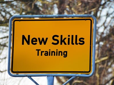 Gelbes Ortseingangsschild mit Schriftzug  "New skills training"