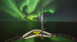 Das Nordlicht (Aurora borealis) strahlt auf das Deck des Forschungsschiffs MARIA S. MERIAN. 