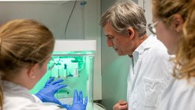 Der DNA-Origami-Schalter lässt sich per elektrischem Feld in Millisekunden umschalten Drei Personen an einer Arbeitsbank mit Petrischale