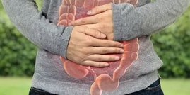 Mensch hält sich den Bauch auf dem der Darm abgebildet ist