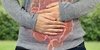 Mensch hält sich den Bauch auf dem der Darm abgebildet ist