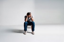 Ein Mann sitz erschöpft auf einem Stuhl